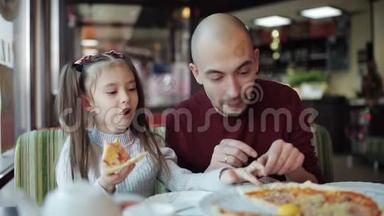 爸爸带着一个小女儿在披萨店里品尝香喷喷的披萨
